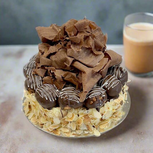 A decadent layered cake with pastry and custard layers, topped with chocolate dipped profiteroles and slivered almonds.